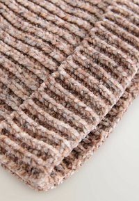 Strukturierte, gerippte Strickdecke in Beige- und Brauntönen, ausgestattet mit einem weichen, voluminösen Garn und einem kuscheligen Finish. Die Kanten sind glatt und leicht umgeschlagen.