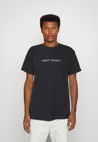Schwarzes Baumwoll-T-Shirt mit dem weißen Text "NIGHT ADDICT" über der Brust. Kurze Ärmel und runder Ausschnitt. Minimalistisches Design.