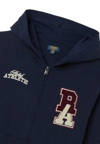 Sudadera con cremallera en color navy, hecha de algodón, que presenta bordado "Rebel ATHLETIC" en blanco y rojo oscuro, con un cuello ajustado y cremallera metálica.