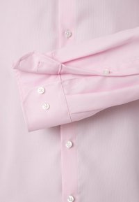 Lichtroze overhemd met lange mouwen, vervaardigd uit een gestructureerde stof, met knoopmanchetten en witte knopen. Getailleerde pasvorm met nette naden en kraagdetail.
