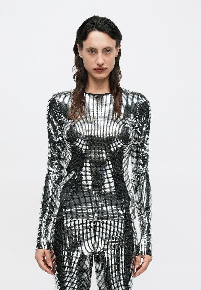 Sädelev, metallikust pika varrukaga top, mis on valmistatud helkivatest litridest, kehakuju rõhutava disainiga hõbedases toonis, sileda tekstuuri ja ümarate kaelustega.