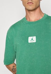Grøn bomulds-t-shirt med rund hals, prydet med et Jordan-logo patch i hvid og grøn. Struktureret stof med en vintage finish.