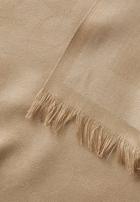 Vevd beige tekstil med et subtilt sirkulært mønster, med frynsete kanter. Glatt tekstur med en fin, tett veving.
