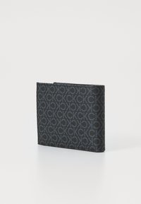 Portafoglio nero con motivo logo in rilievo, forma rettangolare, texture liscia e profilo sottile. Chiusura con zip nella parte superiore.