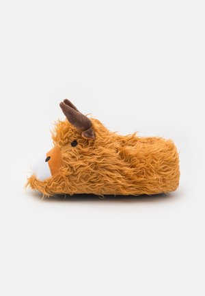 Puszysty pomarańczowy kapcioch w kształcie wysokogórskiego bydła, z białą twarzą, brązowymi rogami i kudłatą teksturą, na jednolitym tle.