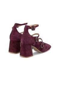 Talons hauts en daim bordeaux avec un bout pointu, un talon carré et des sangles décoratives ornées de bijoux autour de la cheville. Fini texturé et détails accentués.