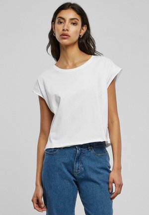 Hvit bomulls t-skjorte med korte oppbrettede ermer, rund hals og en løs passform, sammen med blå denim jeans. Glatt tekstur, minimalistisk design.