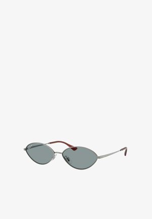 Gafas de sol de metal con forma de ojo de gato alargado, lentes grises y montura delgada en plata. Las patillas tienen un acento rojo.