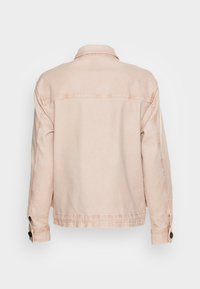 Giacca in denim rosa chiaro con colletto, polsini con bottoni e cuciture visibili. Presenta uno classico yoke posteriore e una silhouette leggermente oversized.