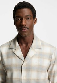 Kurzarm-Hemd im karierten Design in Beige und Hellblau mit weicher Textur. Verfügt über einen angeschrägten Kragen und ein dezent gesticktes "BOSS"-Logo.