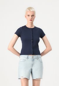 Haut en maille côtelée marine à manches courtes avec fermeture à boutons ; associé à un short en denim déchiré bleu clair. Design simple et décontracté.