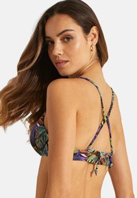 Bikini bovenstuk in een tropisch bladmotief met verstelbare bandjes, voorzien van een gekruist rugontwerp en een gladde, elastische stof in levendige kleuren.