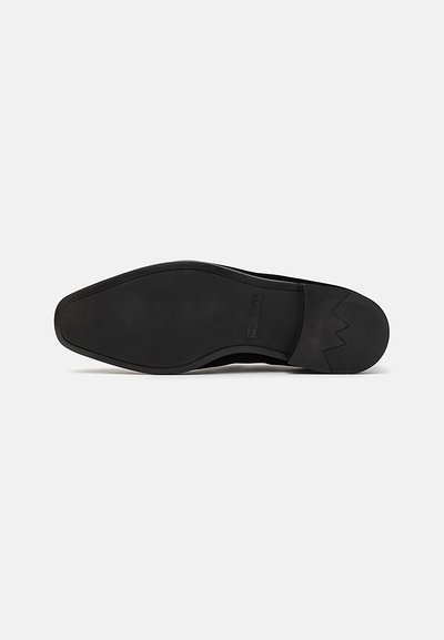 Schwarze Leder-schuhsohle mit einer glatten, flachen Oberfläche und einer spitzen Form. Verfügt über ein Zickzackmuster an der Ferse. Minimalistisches Design.