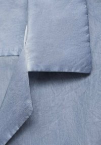 Tessuto blu chiaro con una texture liscia, caratterizzato da un bordo piegato e da una leggera lucentezza, che presenta un design pulito e minimale.