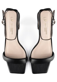 Schwarze Leder-Plateausandalen mit quadratischer Zehenpartie, verstellbarem Knöchelriemen und glattem beigen Fußbett. Mit einem klobigen Absatz und minimalistischem Design.