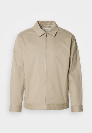 Beige lightweight jacket featuring a collared neck, front zipper, and embroidered logo on the left chest. Smooth texture with a tailored fit.