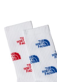 Valkoiset ribattu sukat, joissa on toistuva logomuotoilu punaisella ja sinisellä. Suunnitelma sisältää useita versioita "The North Face" -tekstistä.