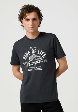 Mørkegrå bomulds T-shirt med hvid grafisk print, der inkluderer tekst og vingemotiver. Klassisk rundhalset design, kortærmede, afslappet pasform.