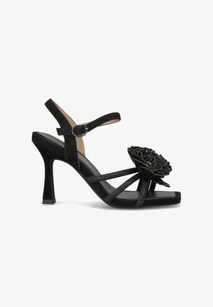 Schwarze hochhackige Sandalen mit einem Wildleder-Finish, mehreren Riemen, einem floralen Akzent aus strukturiertem Material und einem quadratischen Zehendesign.