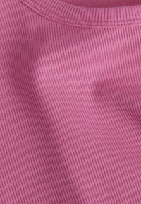 Geribbeld roze stof met een zachte textuur, voorzien van een ronde halslijn en subtiele rek, ideaal voor comfortabele draagbaarheid.