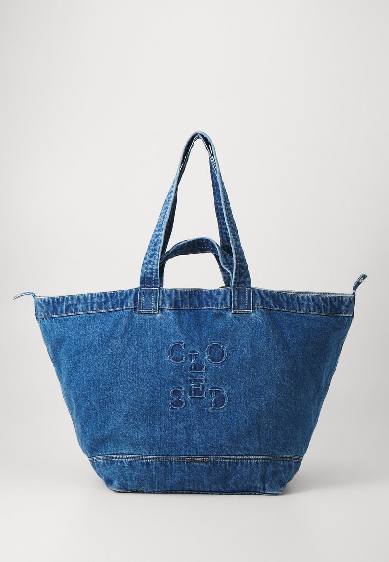 Denim tote bag in blue with two sturdy handles, featuring embossed text design “CLOSED” on the front, spacious and structured shape.