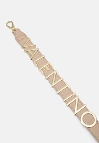 Tan leren riem met de naam "VALENTINO" in bold gouden letters en een cirkelvormige accent, afgewerkt met een clip bevestiging.