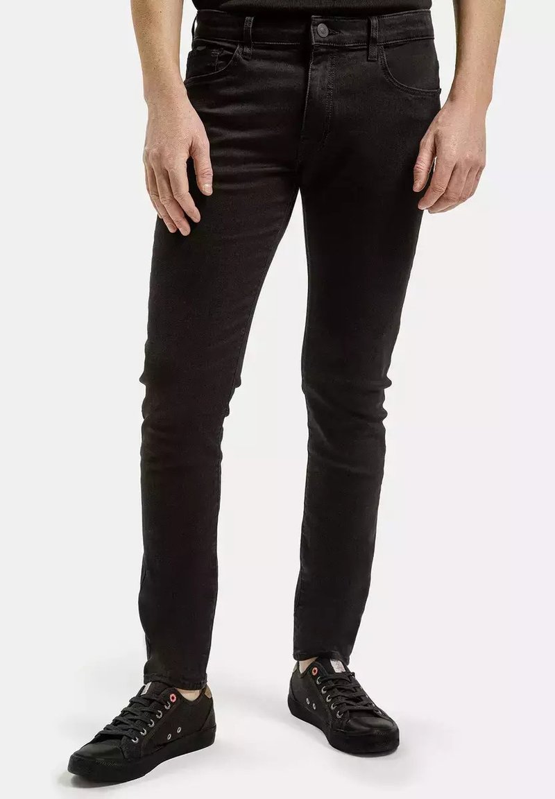 Czarne dżinsy w slim fit, pięć kieszeni i zapięcie na guzik. Połączone z ciemnymi trampkami o teksturowanej powierzchni i miękkimi sznurowadłami.