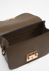 Olivengrøn lædertaske med en guldfarvet lukning, der har et rummeligt indre og en glat tekstur. Indeholder flere lommer til organisering.