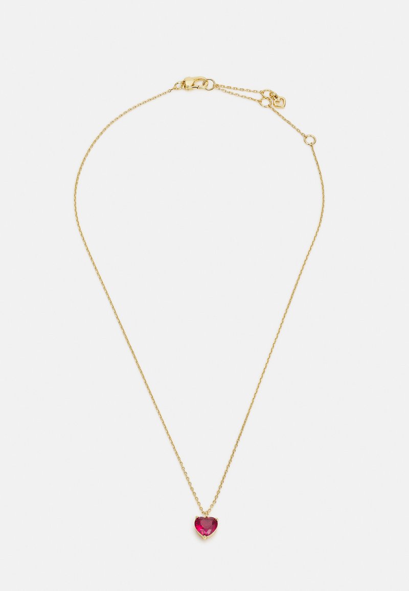Gold chain necklace featuring a heart-shaped ruby pendant, which has a faceted surface and is set in a gold prong setting.