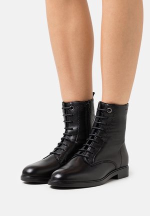 Bottines en cuir noir à bout rond, avec un laçage à l'avant, une fermeture éclair sur le côté et une semelle plate. Texture lisse avec des coutures discrètes.