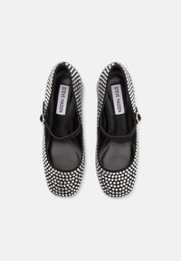 Pantofi negri cu embellishments din strasuri argintii, vârf rotund și o brățară peste glezna piciorului. Căptușeală interioară netedă și talpă plată.