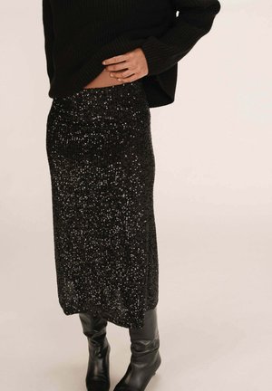 Jupe en sequins noirs au design ajusté, arrivant au genou, avec une surface texturée. Associée à des bottes noires montantes.