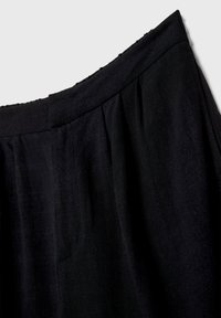 Črna krila z teksturirano tkanino, ki ima nabrano elastiko in naborke za dodano dimenzijo. Preprost, eleganten dizajn z gladkim zaključkom.