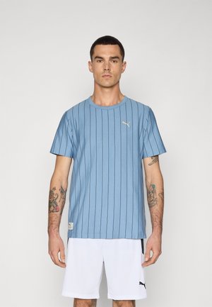 Light blue short-sleeve t-shirt with vertical stripes, round neck, and a small gold Puma logo on the chest. Featured with white shorts.