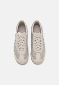 Beiga sneakers med ovandel i mesh och detaljer i mocka. Har tre grå ränder, runda skosnören och en vadderad innersula. Platt gummisula.