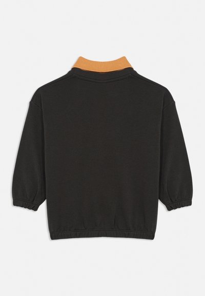 Pull-over noir à manches longues avec poignets et taille élastiques, doté d'un col côtelé orange contrastant, vu de dos.