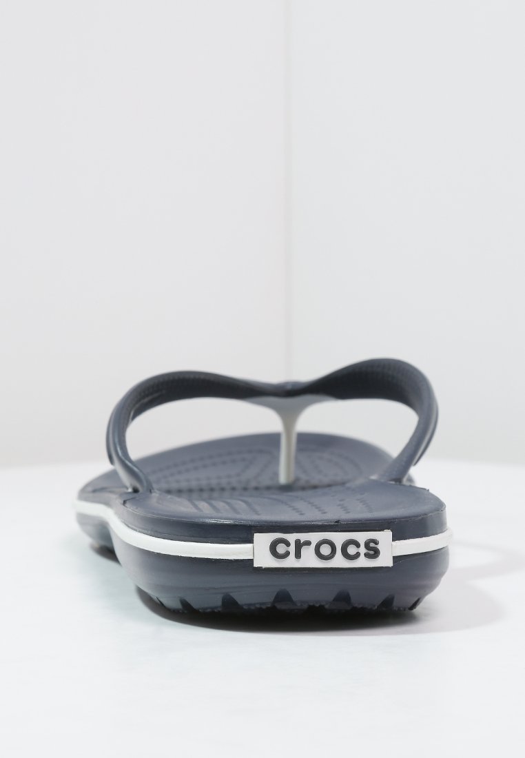 Chanclas de color azul marino con plantilla texturizada, correas flexibles y línea de acento blanca. Presenta el logo de "crocs" en el talón.