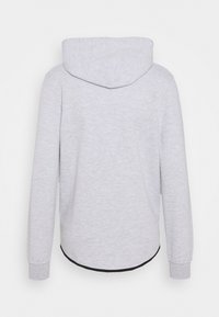 Sweat-shirt à capuche gris clair à manches longues, poignets côtelés et ourlet légèrement arrondi avec bordure noire, vu de dos.