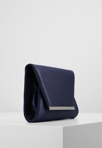Pochette en satin bleu marine avec une texture lisse, design à rabat, et un accent métallique rectangulaire sur le devant. Forme carrée.