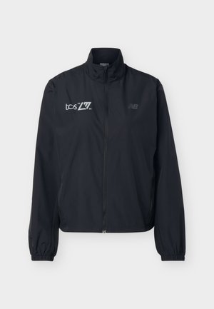 Black full-zip lightweight jacket with high collar, elastic cuffs, and white "tcs 2026" and subtle "NB" logos on the front.