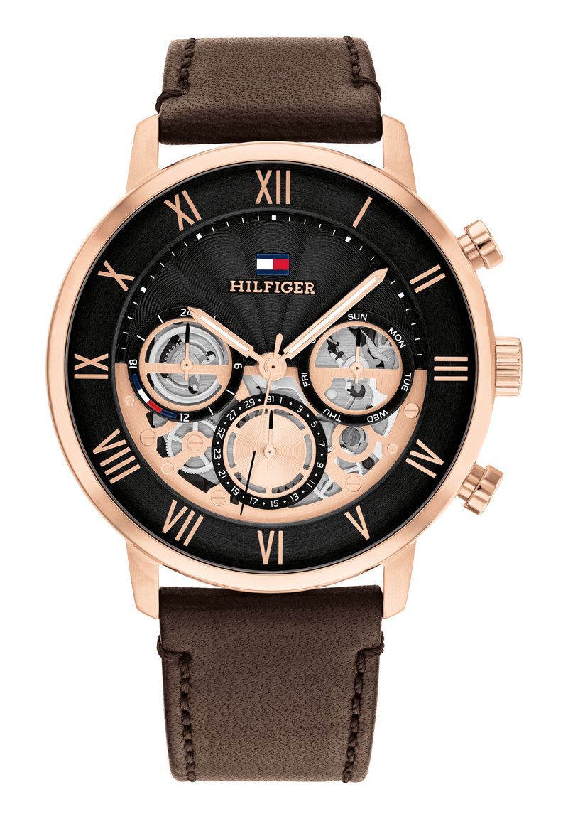 Montre chronographe avec un cadran noir et des accents dorés roses, dotée d'un bracelet en cuir marron, de chiffres romains et de rouages visibles.