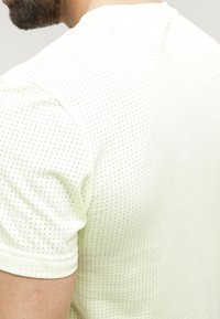 Camiseta de manga corta verde claro con un patrón texturizado; presenta un escote redondo y una tela suave para mayor comodidad.