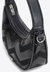 Černá kabelka se vzorem v chevronu z flitrů, s hladkým koženým popruhem a zipovým uzávěrem, která ukazuje texturovaný povrch.