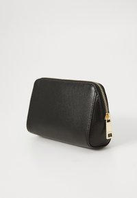 Borsa cosmetica in pelle nera testurizzata con zip dorata su sfondo bianco.