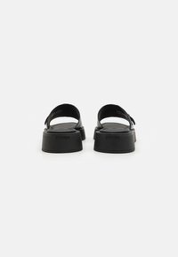 Sorte platform sandaler med minimalistisk design, lavet af glat materiale med en bred rem og en formet sål.
