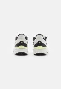 Chaussures de sport pour homme avec une tige en mesh blanc, des accents noirs et une semelle vert lime. Elles disposent d'un col rembourré et d'une semelle extérieure texturée.