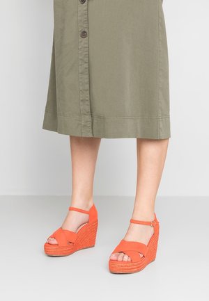 Sandales wedges orange avec une plateforme tissée texturée et une lanière de cheville. Brides croisées à l'avant ; tige en tissu doux ; hauteur de talon d'environ 7 cm.
