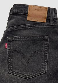 Πίσω τσέπη μαύρου τζιν Levi's με κόκκινη ετικέτα Levi's και καφέ δερμάτινο πατς επωνυμίας στη ζώνη μέσης.