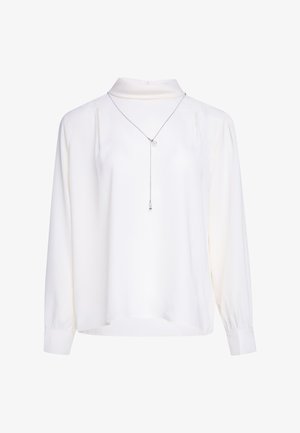 Weiße Bluse mit langen Ärmeln und hohem Kragen, leicht gepufften Ärmeln, Bündchen an den Handgelenken und einer zarten silbernen Lariatkette mit zwei kleinen Anhängern.