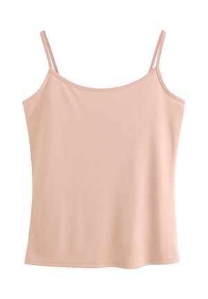 Žena s dlhými hnedými vlasmi, oblečená v béžovom tielku a zodpovedajúcom krajkovanom spodnom prádle, otočená chrbtom k jednoduchému svetlému pozadiu.